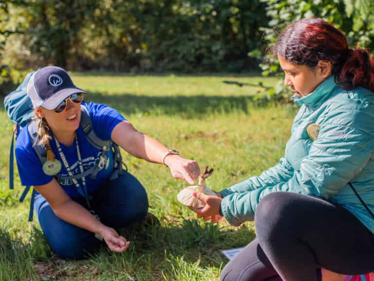 Student holding a mushroom with a teacher pointing to its structure