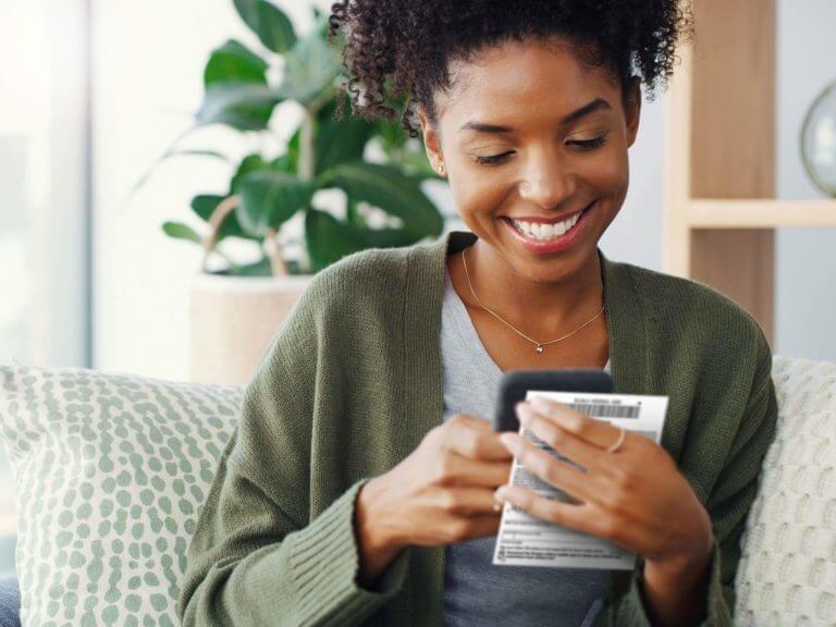 woman sitting on couch, scanning a Scratch-it ticket on her phone