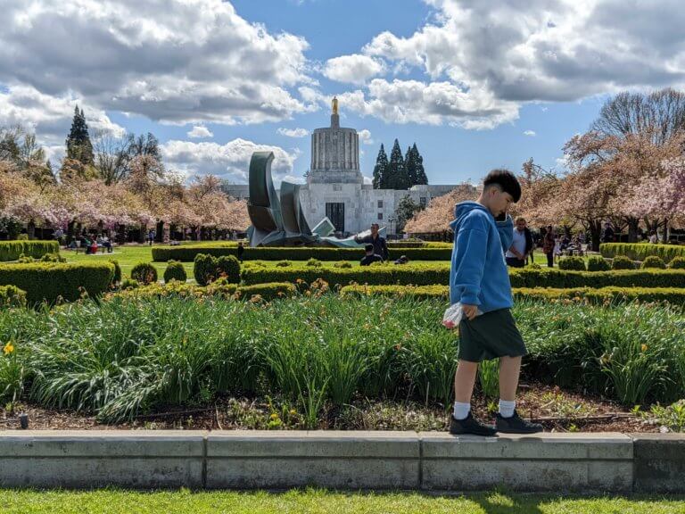 A boy walks in front of the Oregon State Capitol